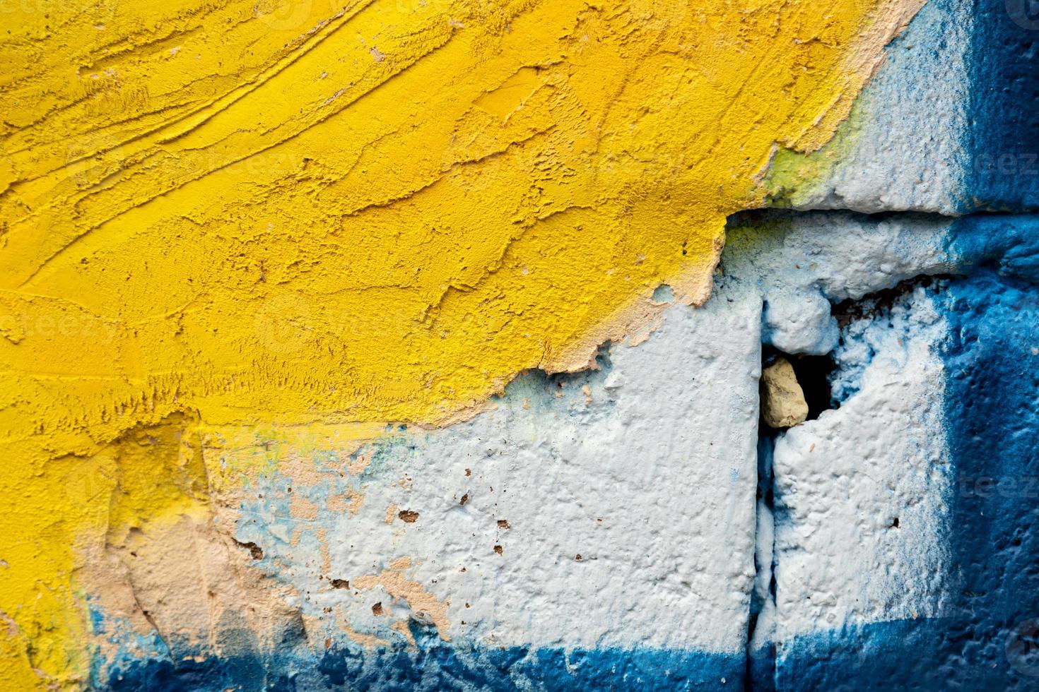 cimento amarelo velho e parede de tijolo azul foto