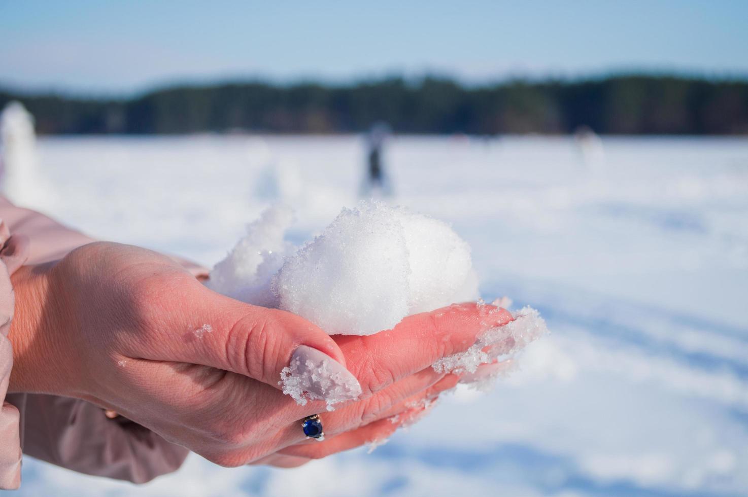 mãos femininas com neve branca em dia de inverno foto