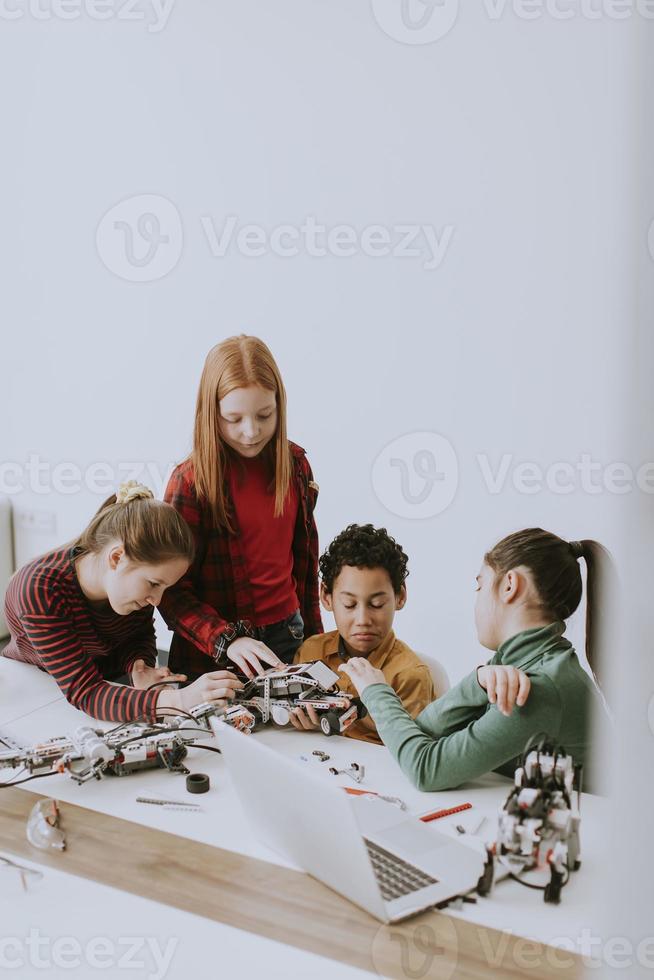 crianças felizes programando brinquedos elétricos e robôs na sala de aula de robótica foto