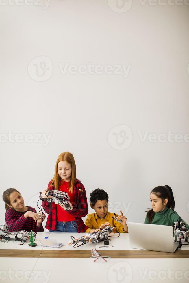 crianças felizes programando brinquedos elétricos e robôs na sala de aula de robótica foto