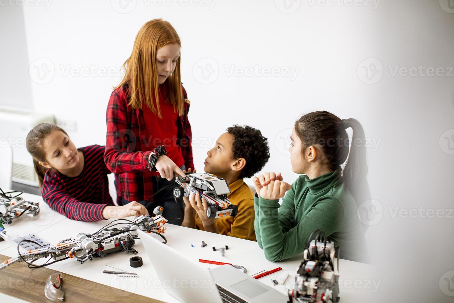 crianças felizes programando brinquedos elétricos e robôs na sala de aula de robótica foto