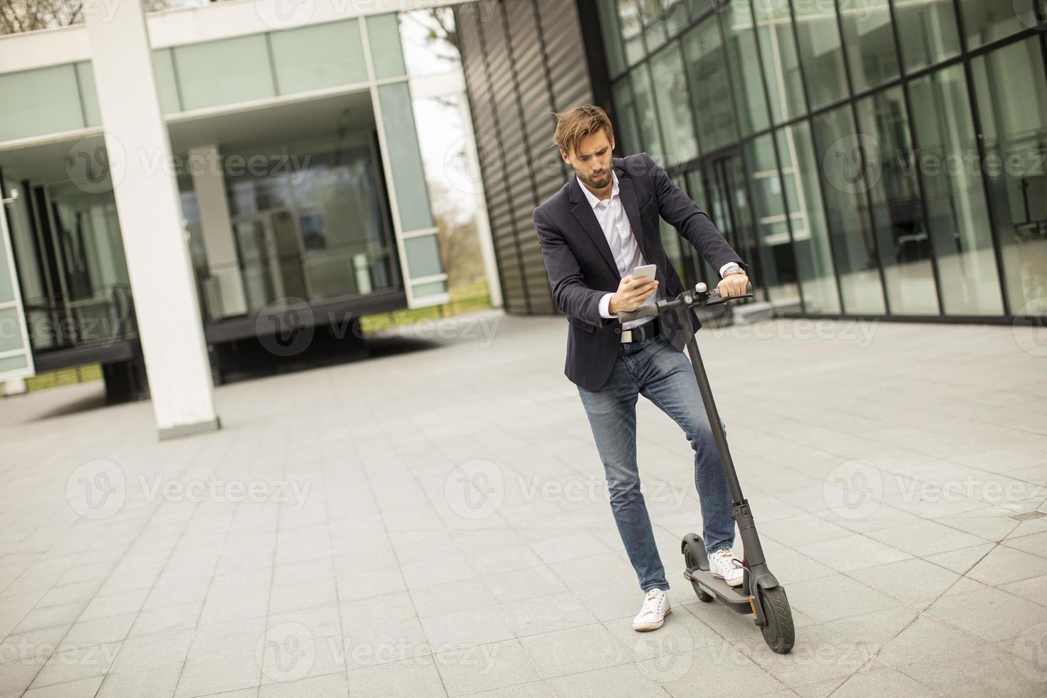 jovem empresário usando telefone celular em scooter elétrico foto