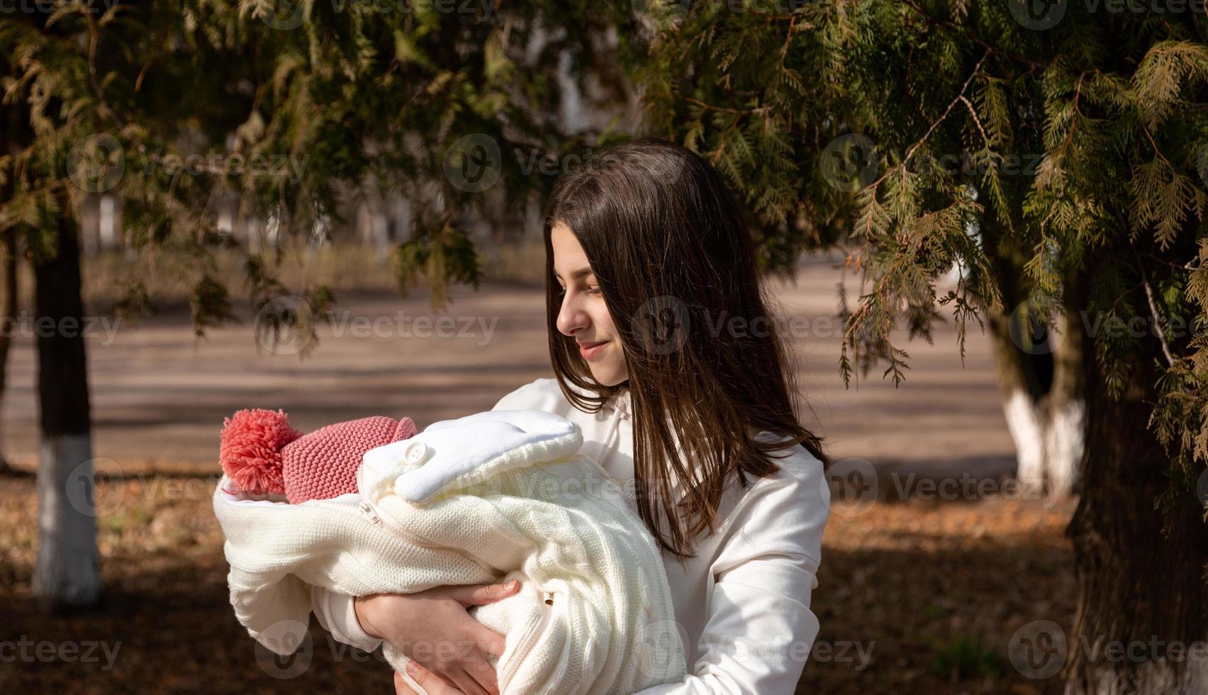 bela jovem segurando um bebê recém-nascido nos braços foto