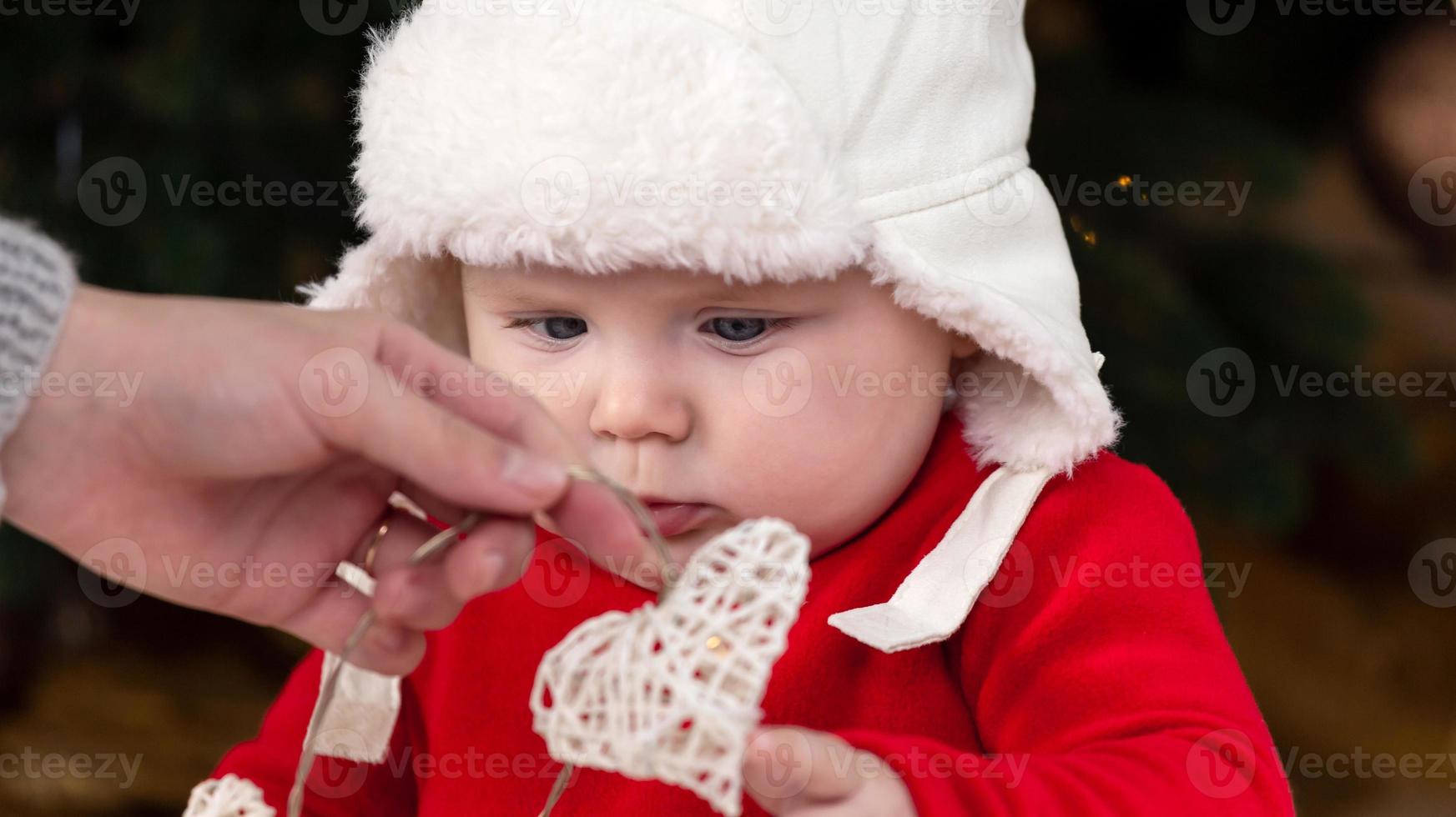 criança de natal olha para uma guirlanda com corações foto