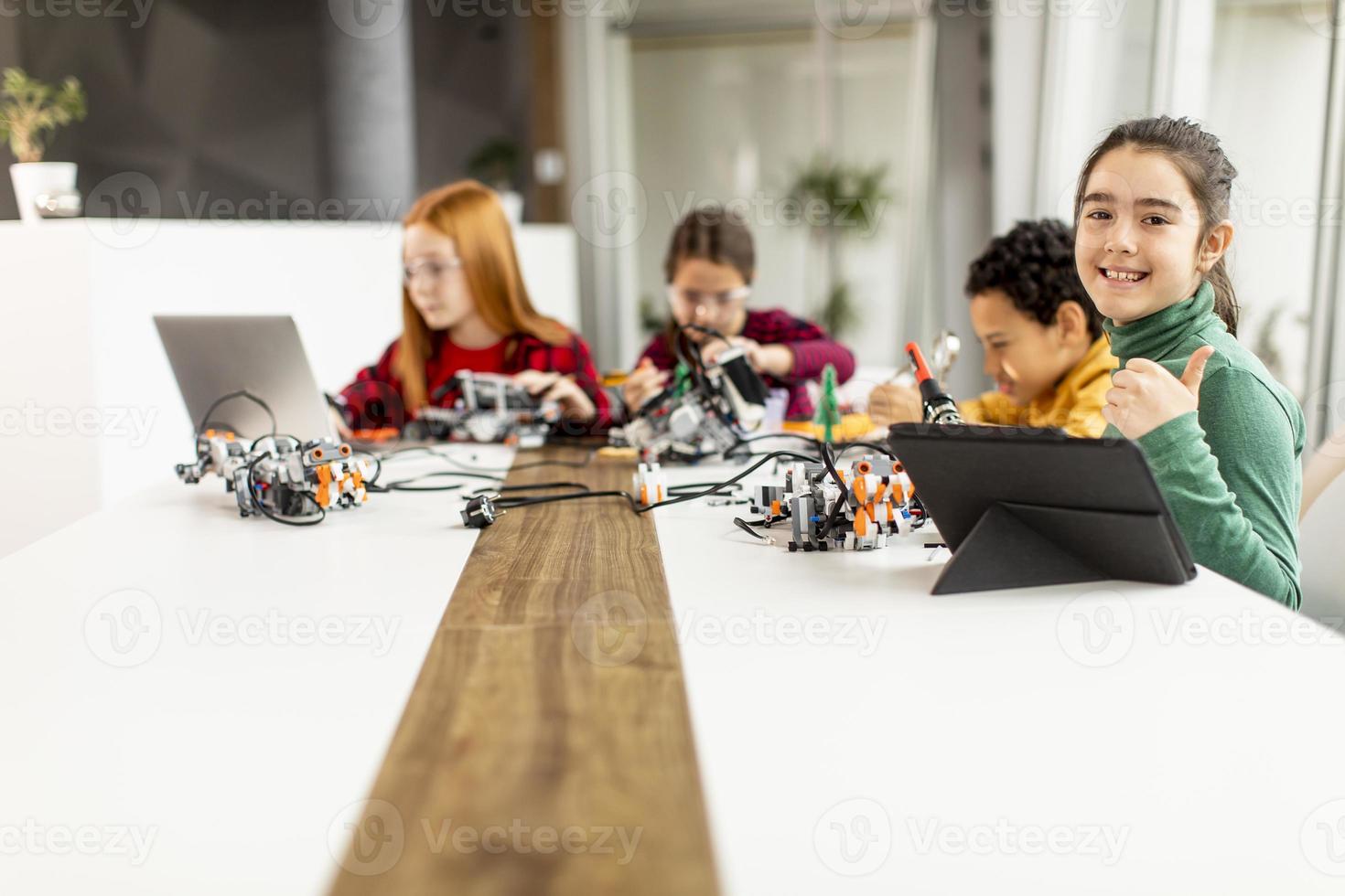 crianças felizes programando brinquedos elétricos e robôs na sala de aula de robótica foto