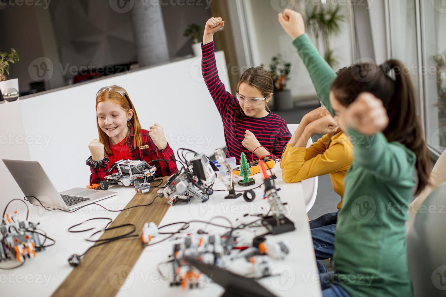 crianças felizes programando brinquedos elétricos e robôs na sala de aula de robótica foto