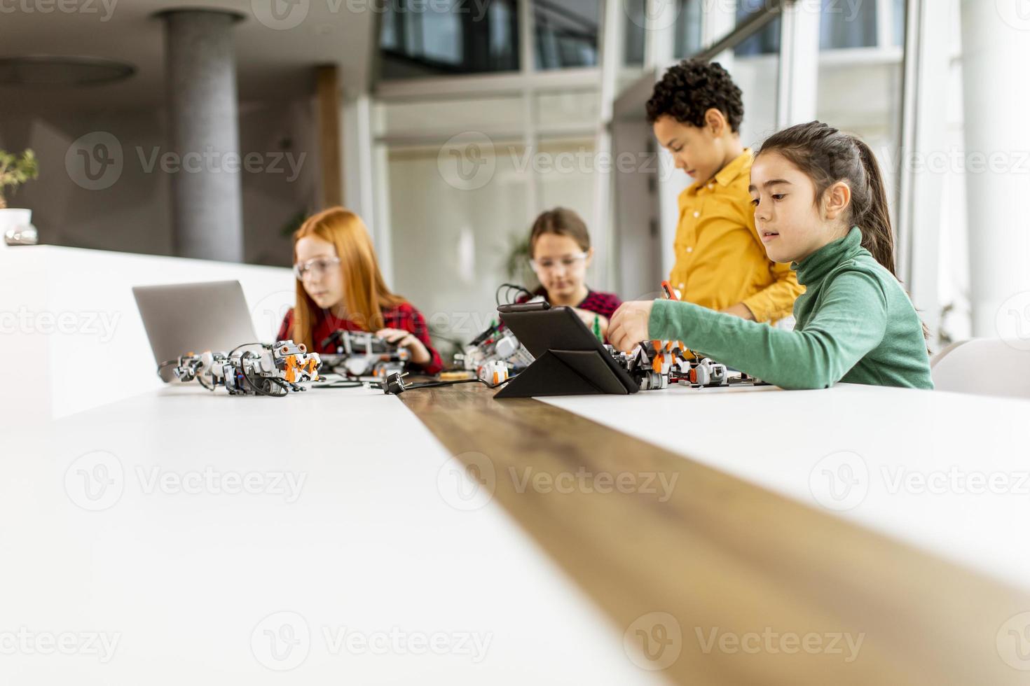 crianças felizes programando brinquedos elétricos e robôs na sala de aula de robótica foto