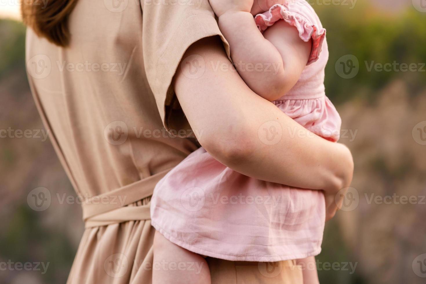 uma jovem mãe olha para a pedreira ou montanhas e segura uma criança nos braços foto