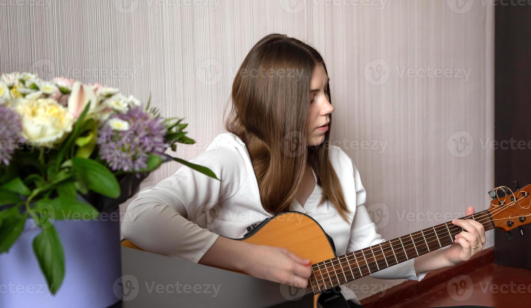 uma menina toca violão sentada no chão de sua casa foto