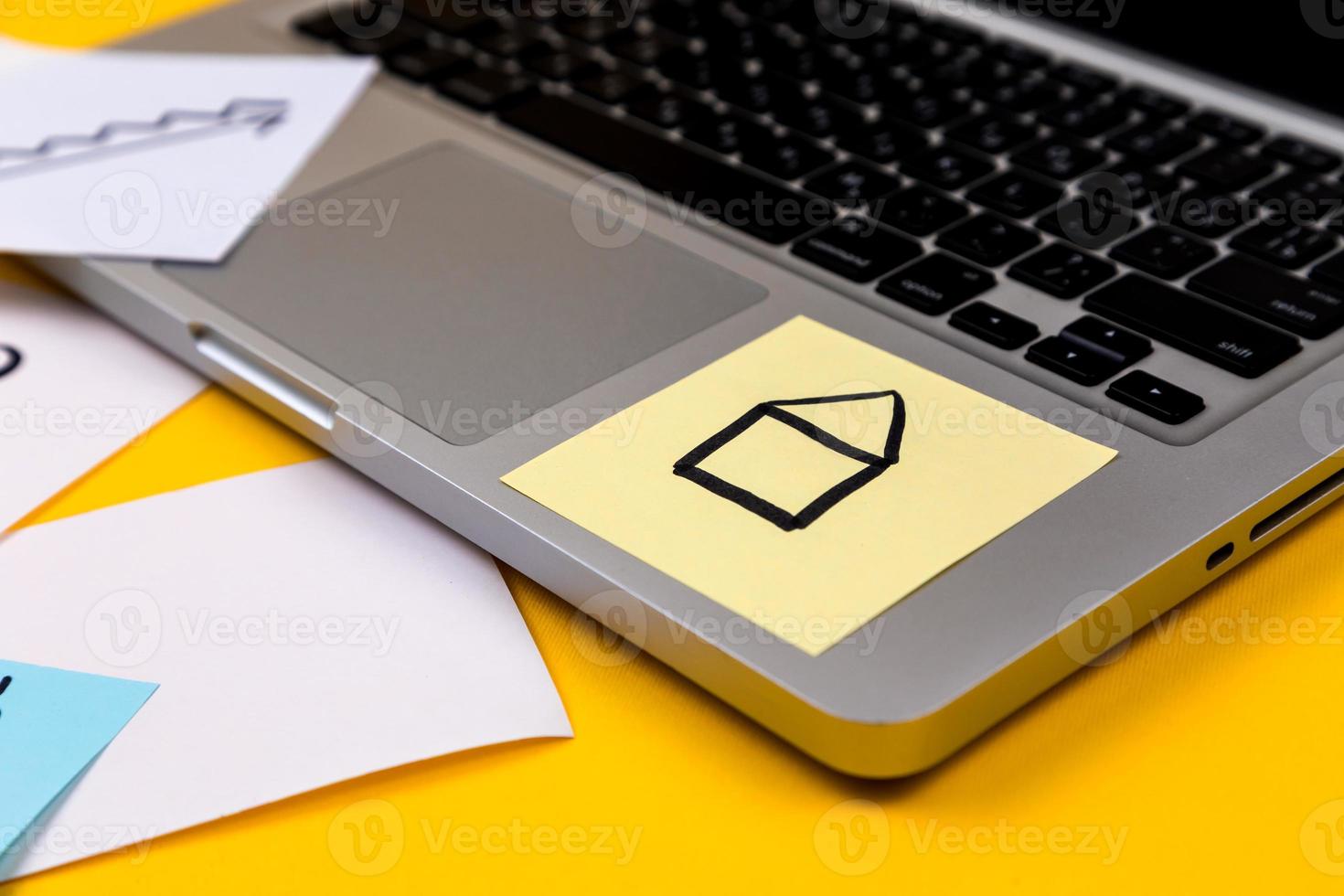 área de trabalho da mesa do escritório em casa com laptop e adesivo de papel no fundo amarelo foto