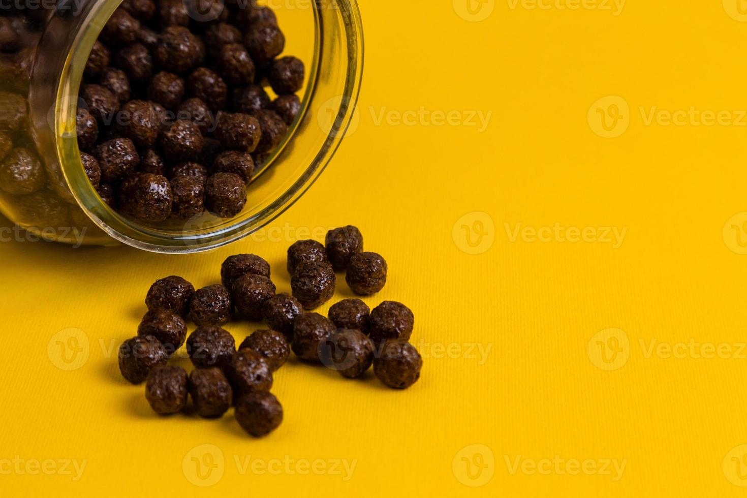 flocos de milho de cereais de chocolate derramando no fundo amarelo foto