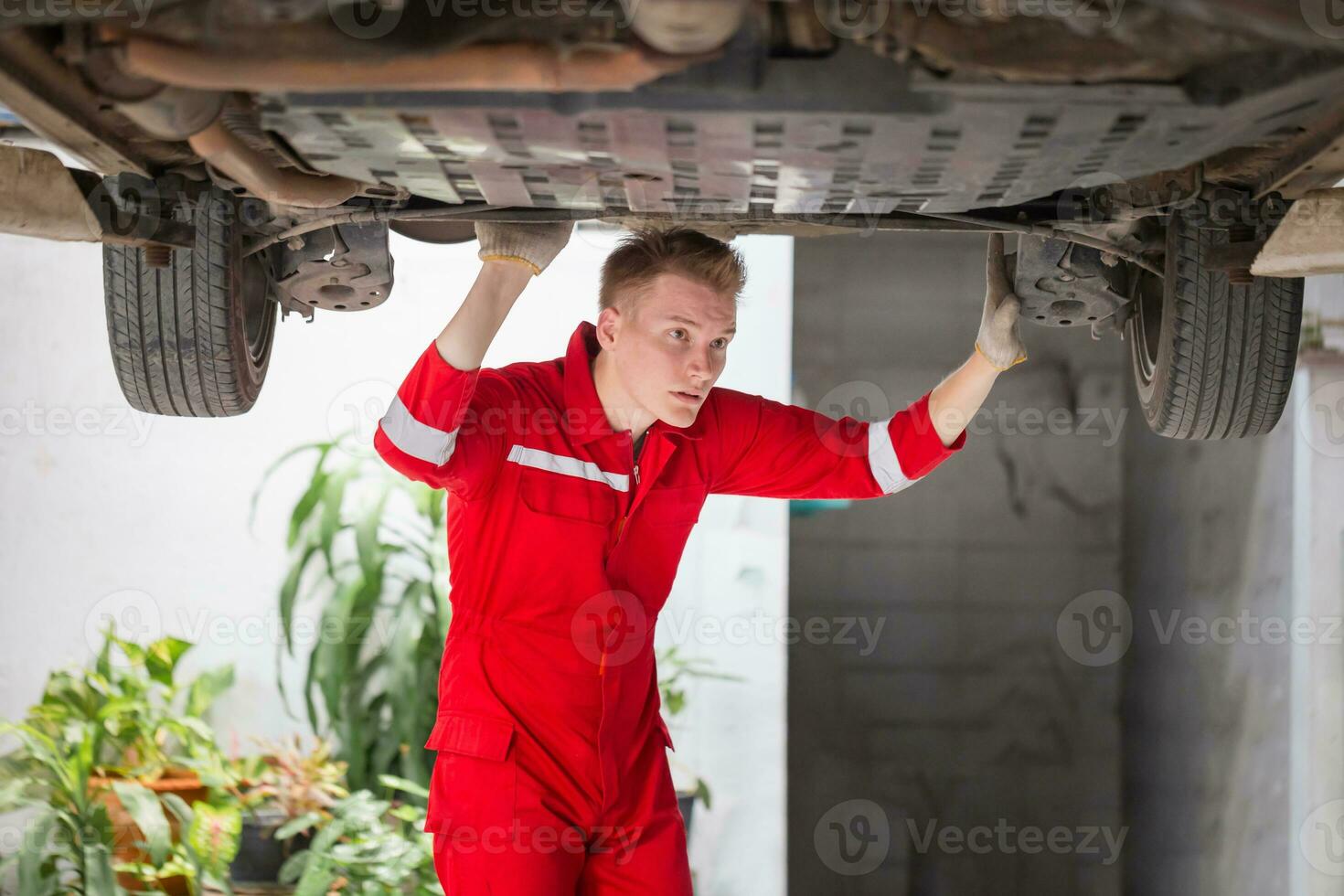 auto mecânico trabalhando dentro garagem, técnico homem trabalhando dentro auto serviço com levantado veículo, carro reparar, e manutenção foto