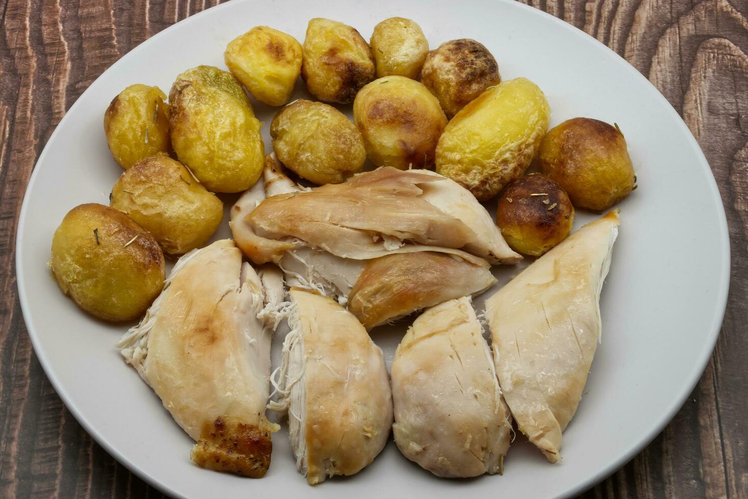 assado cozido frango e batatas em branco prato. foto