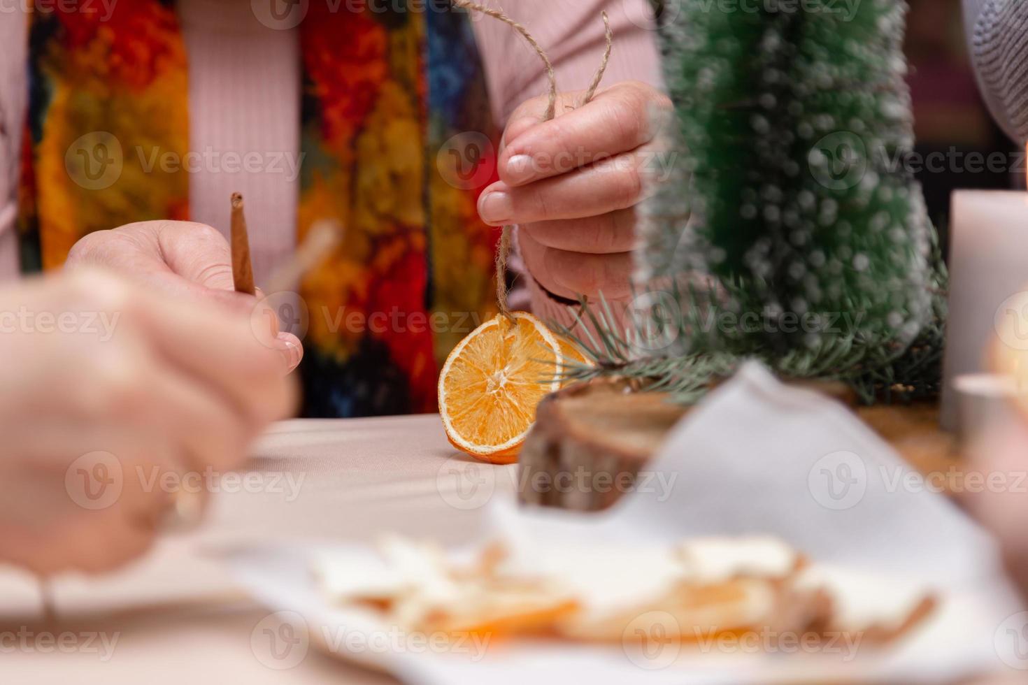 Mulheres fazendo enfeites à mão com laranjas secas foto