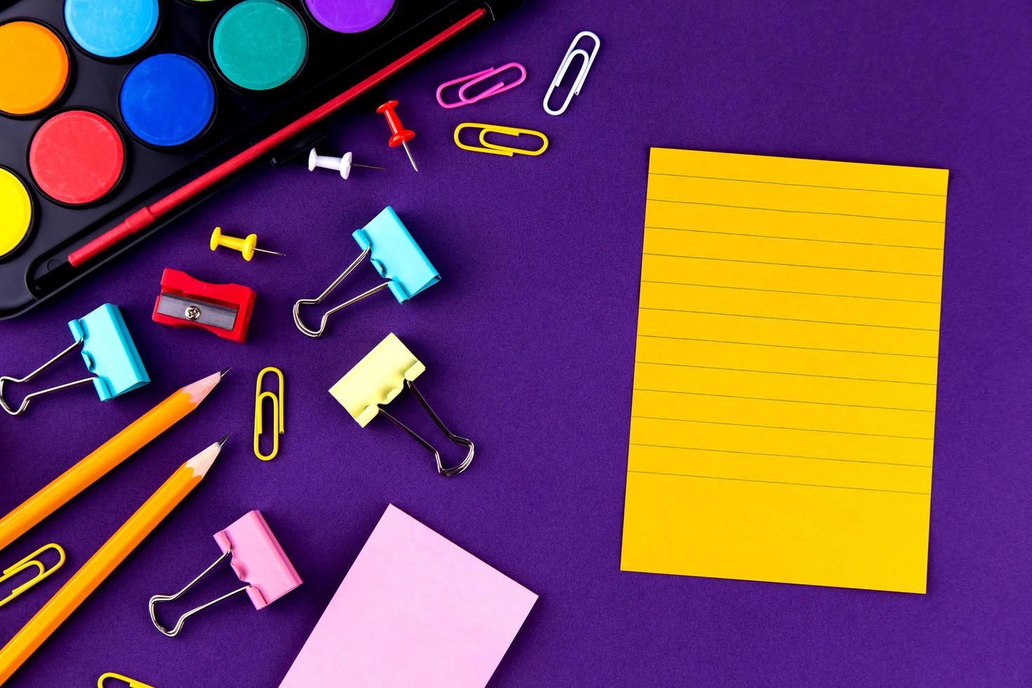 artigos de papelaria de material de escritório escolar em um fundo roxo foto