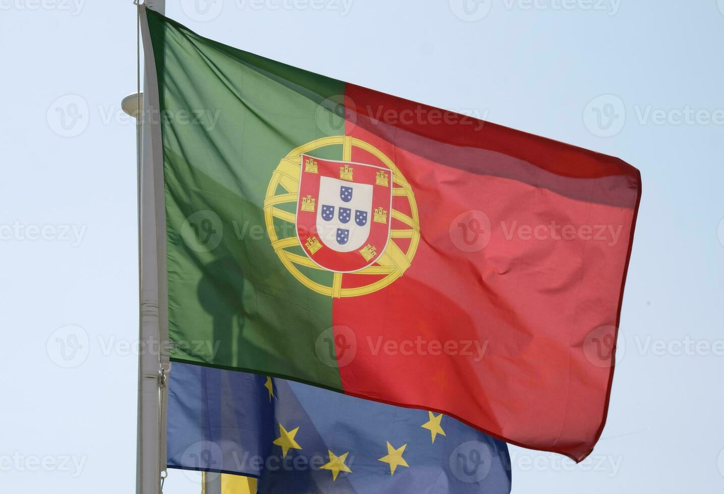 Português nacional bandeira e bandeira do a europeu União acenando dentro a vento foto
