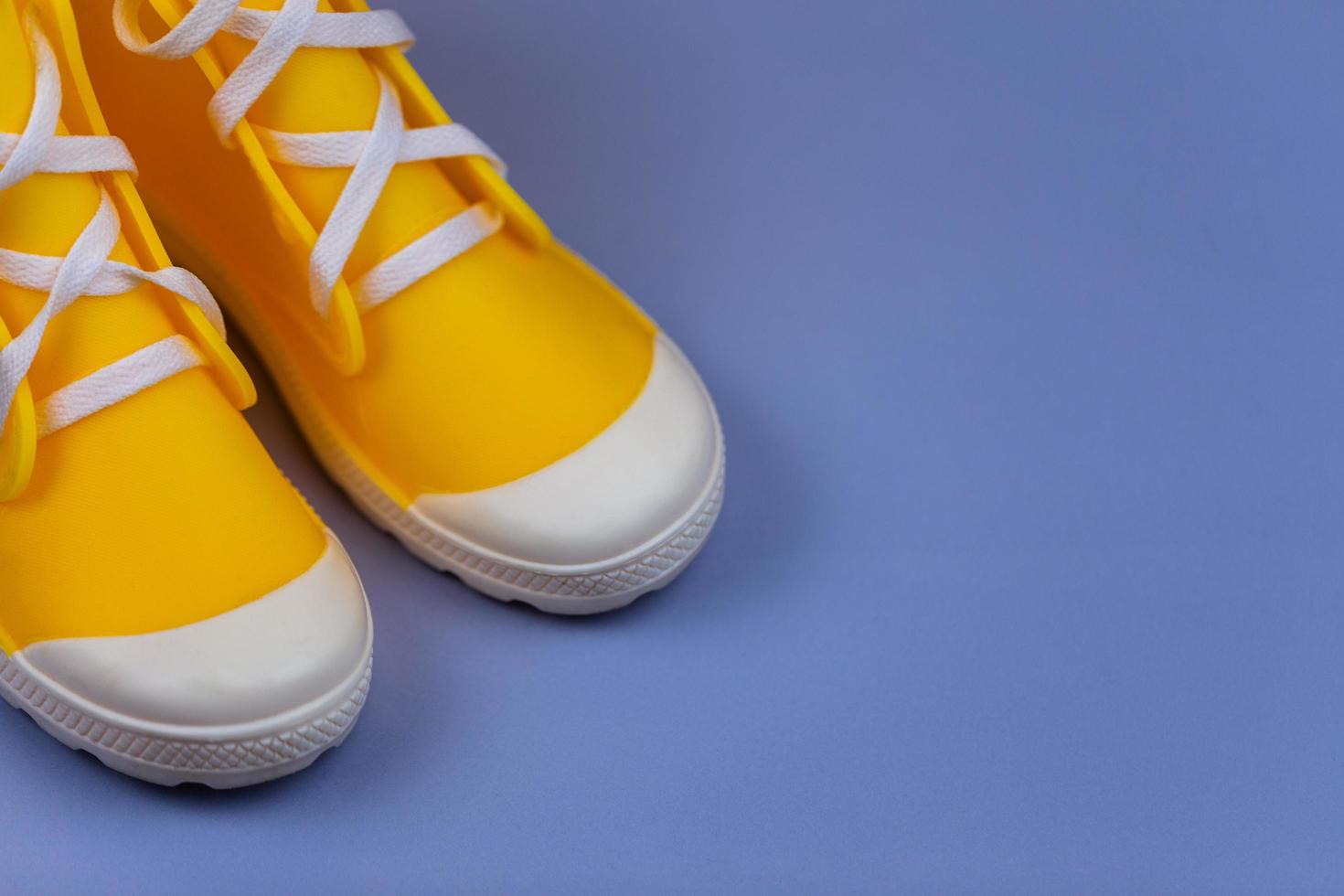 botas de borracha amarelas isoladas em fundo roxo com espaço de cópia foto