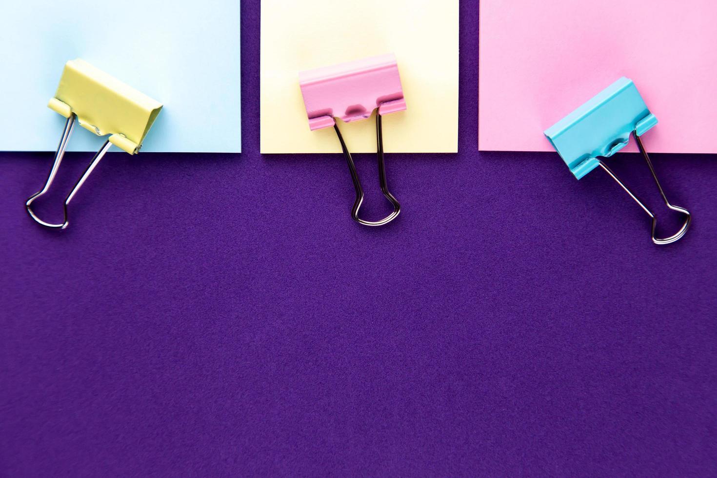 bloco de notas com conjunto de clipes de papel coloridos em fundo roxo foto