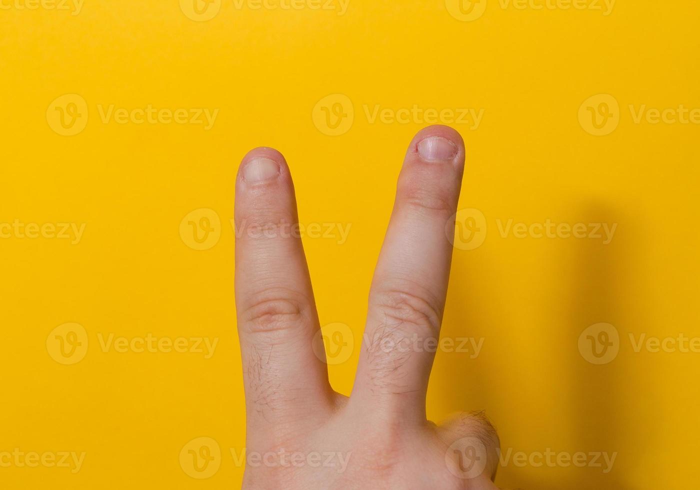 dedos com unhas roídas isoladas em um fundo amarelo foto