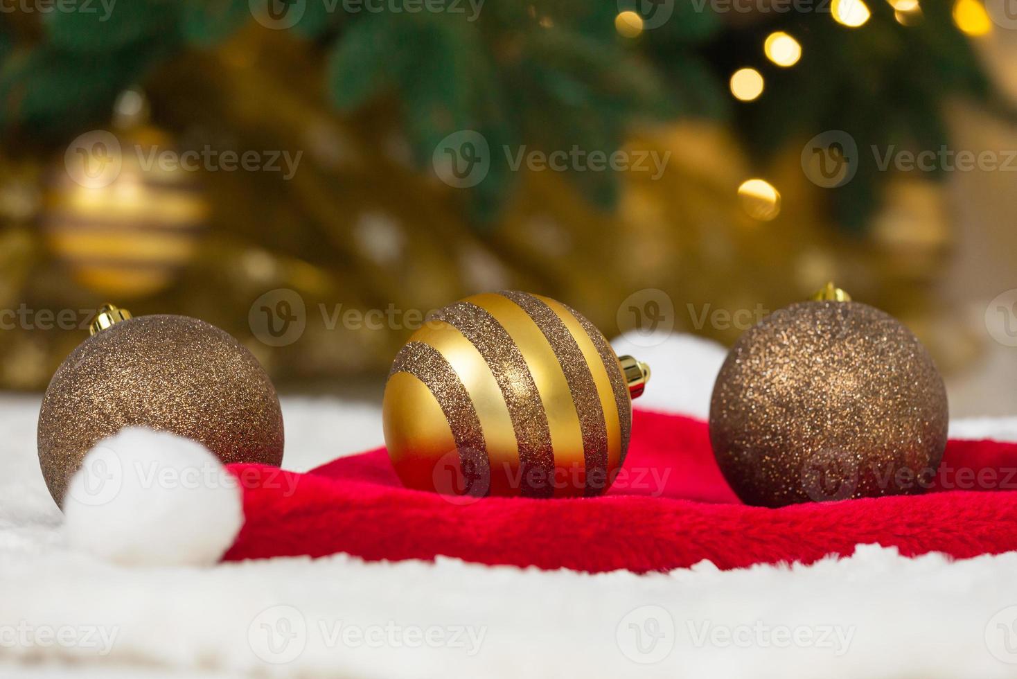 bugigangas douradas com chapéu de Papai Noel e árvore de Natal foto