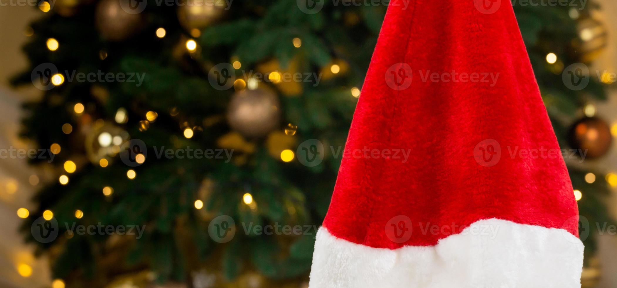 chapéu de papai noel no fundo de uma árvore de natal e guirlandas foto