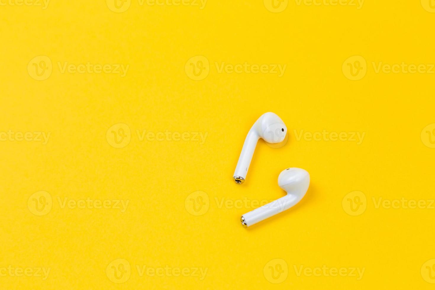 fones de ouvido brancos em fundo amarelo com espaço de cópia foto