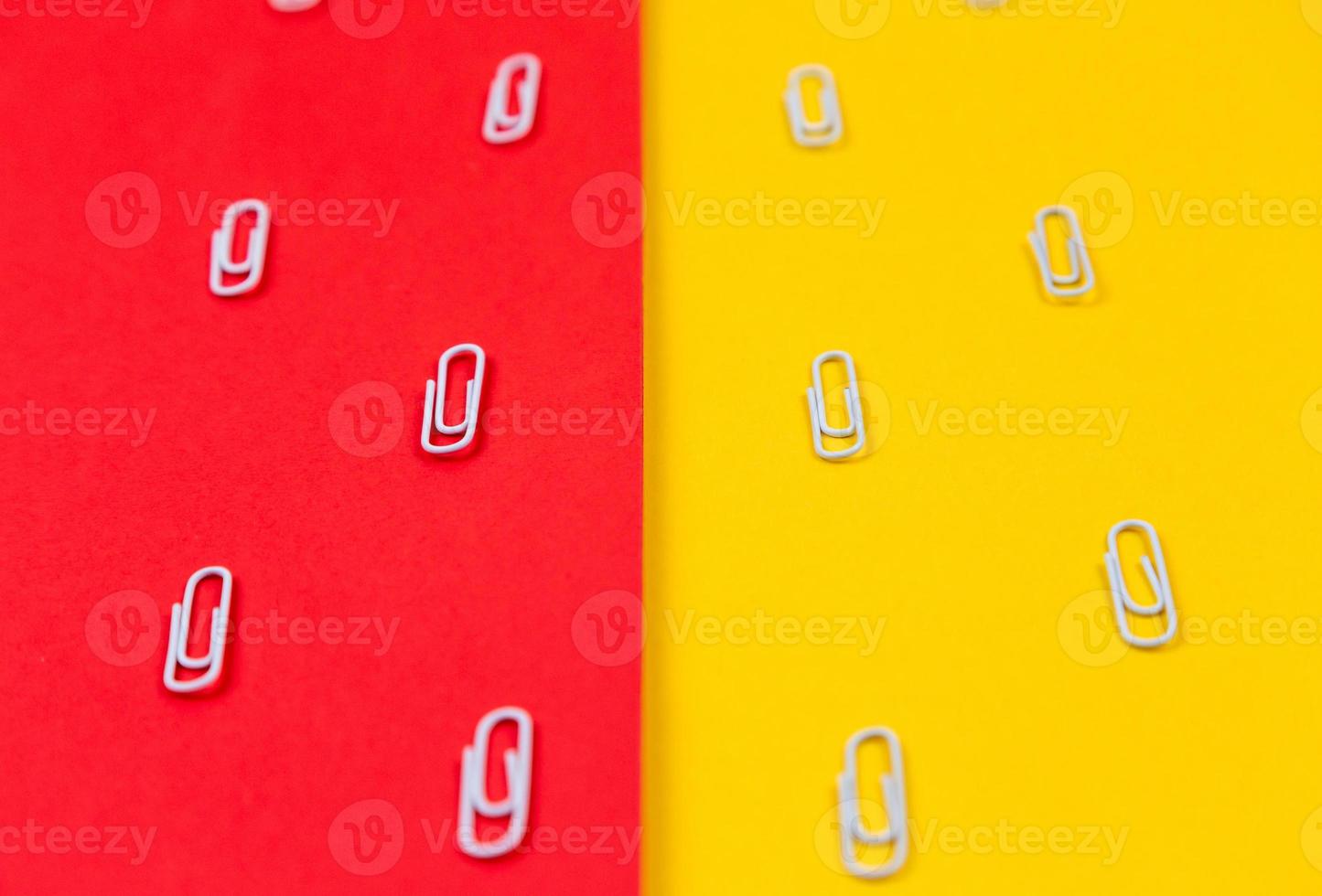 close-up de clipes de papel brancos em um fundo vermelho e amarelo foto