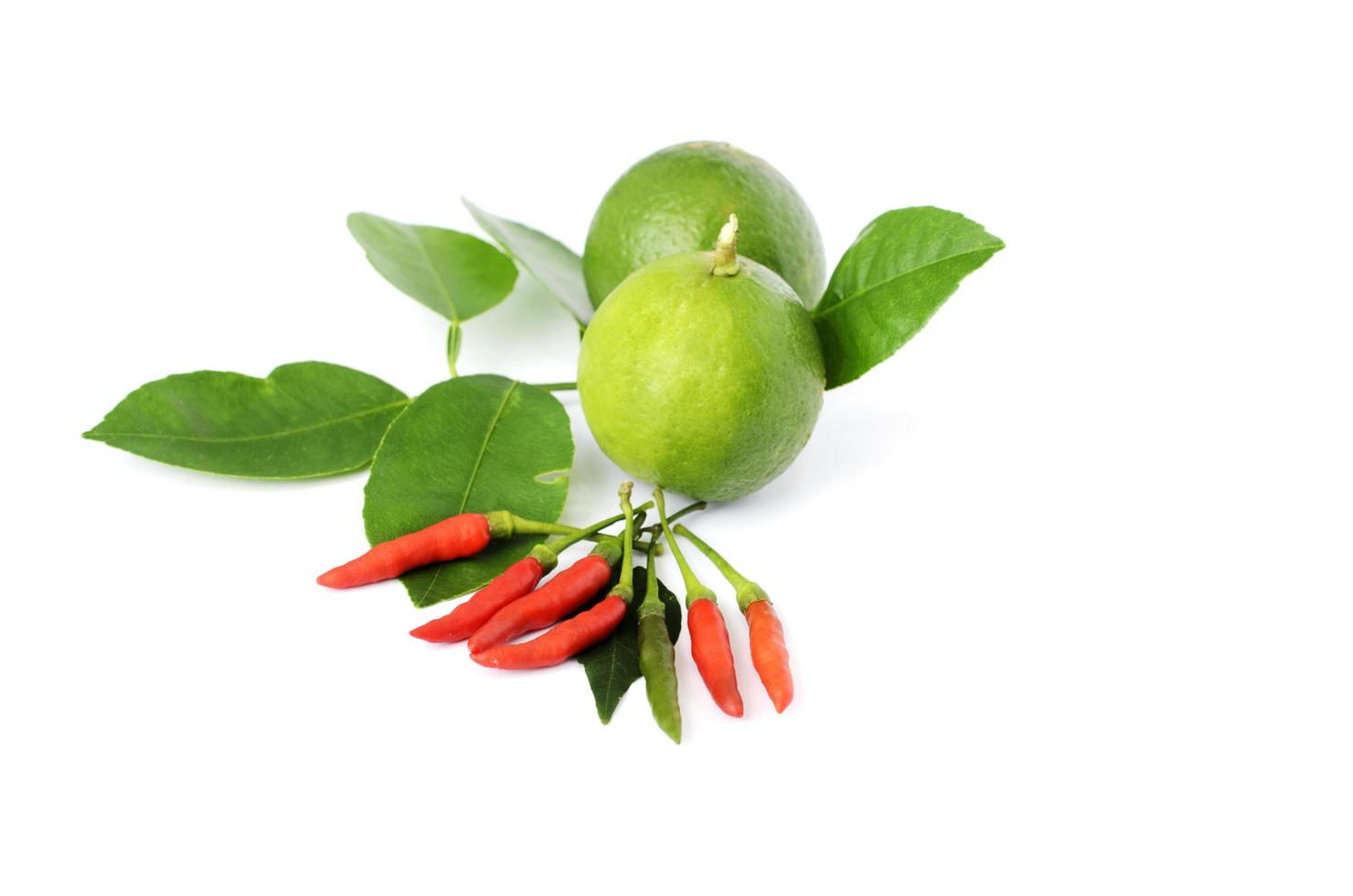 limão verde e folhas com pimenta no fundo branco foto