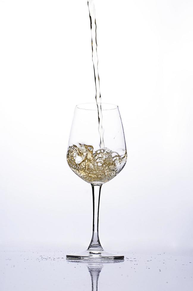 derramando cerveja em uma taça de vinho em fundos brancos foto