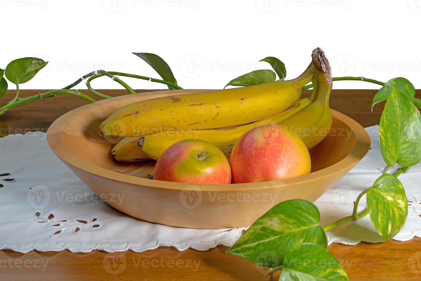 mão virou tigela de madeira com bananas e carrinhos de maçã em uma mesa foto