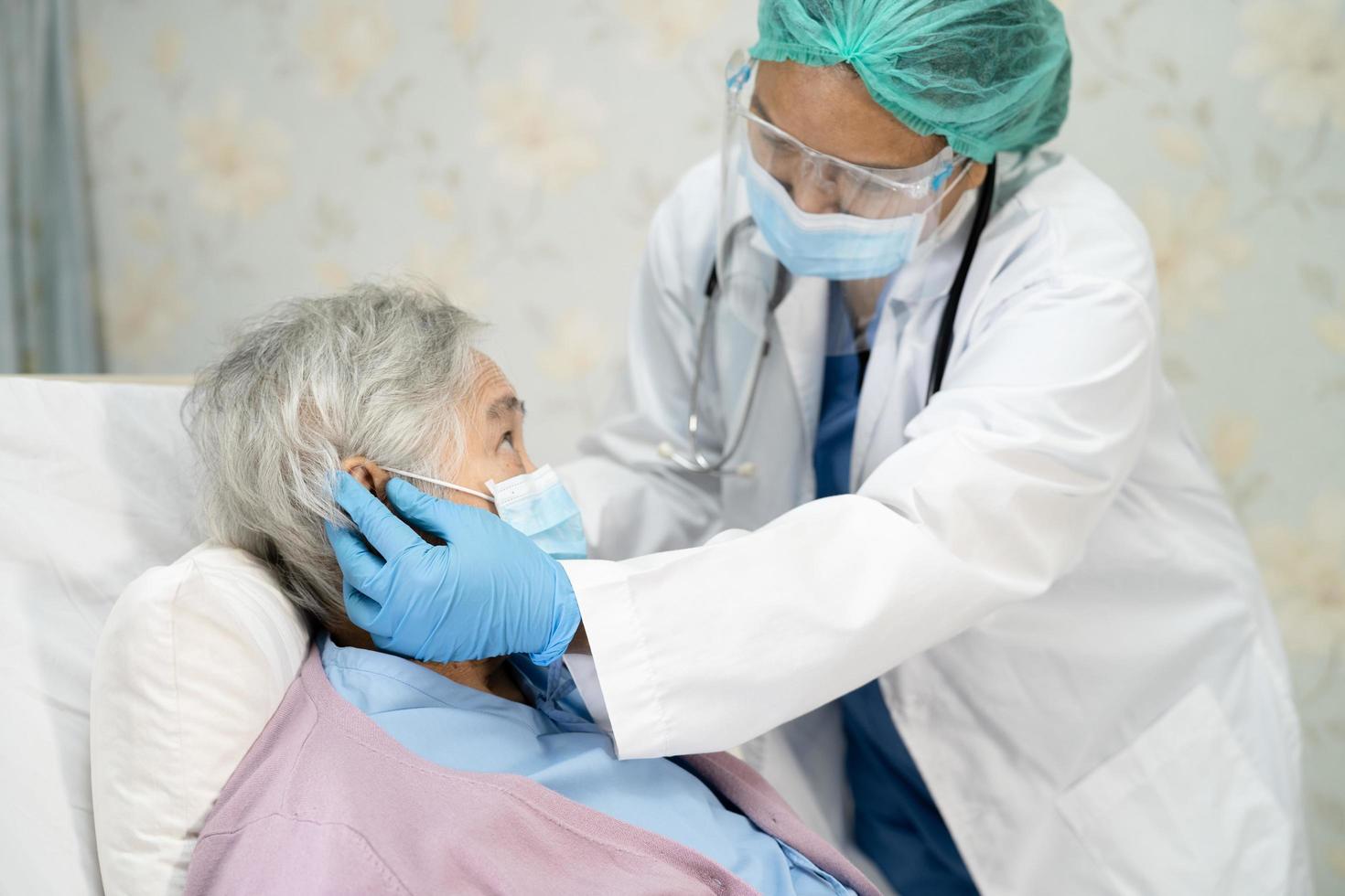 médico usando estetoscópio para verificar paciente mulher idosa ou idosa asiática usando máscara facial no hospital para proteção contra infecção covid 19 coronavírus foto