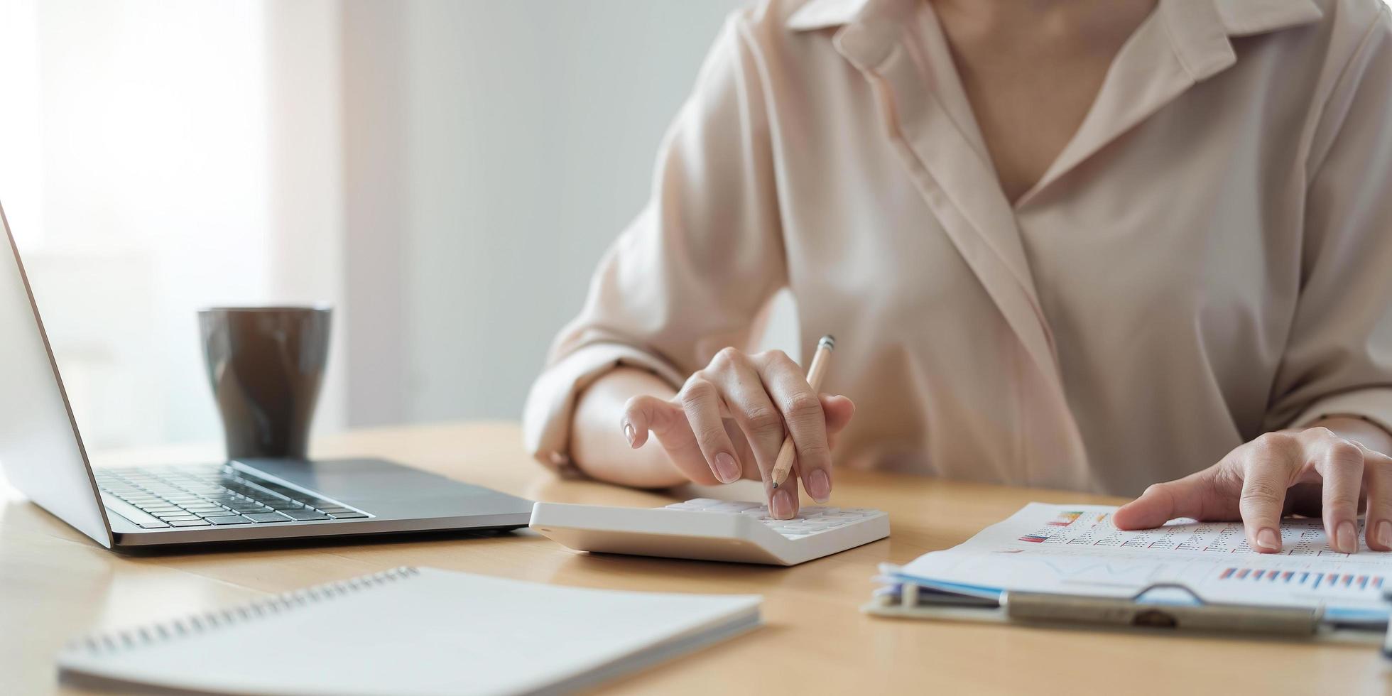 mulher de negócios que trabalha em finanças e contabilidade analisa orçamento financeiro com calculadora e laptop no escritório foto