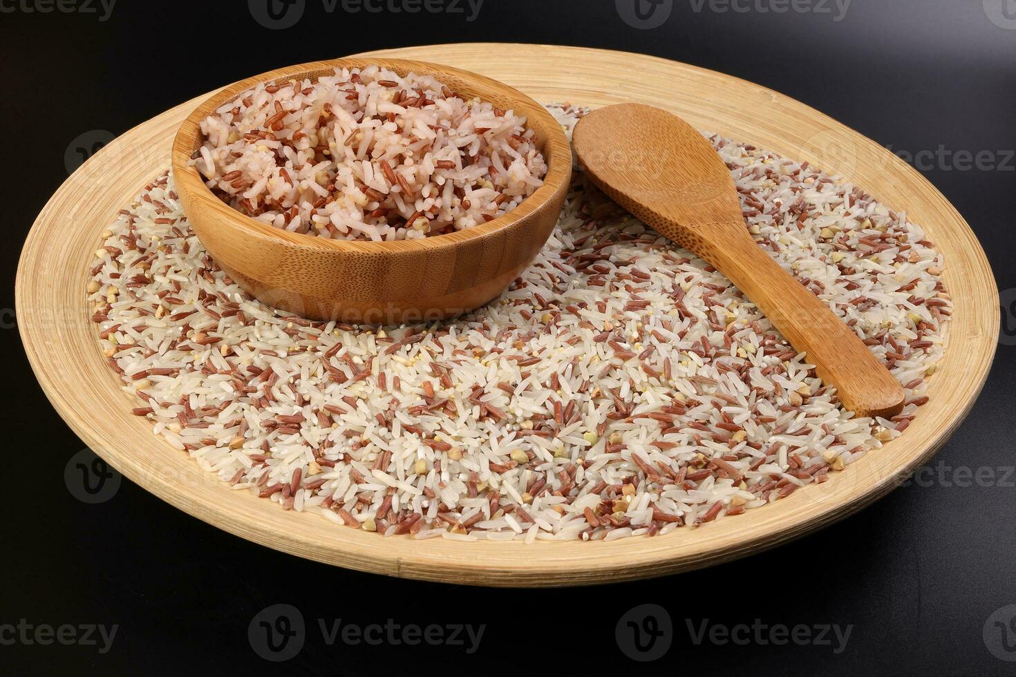 cozinhou e cru misturado baixo glicêmico índice saudável arroz grão basmati painço trigo sarraceno vermelho arroz dentro de madeira tigela sobre de madeira prato colher em Preto fundo foto