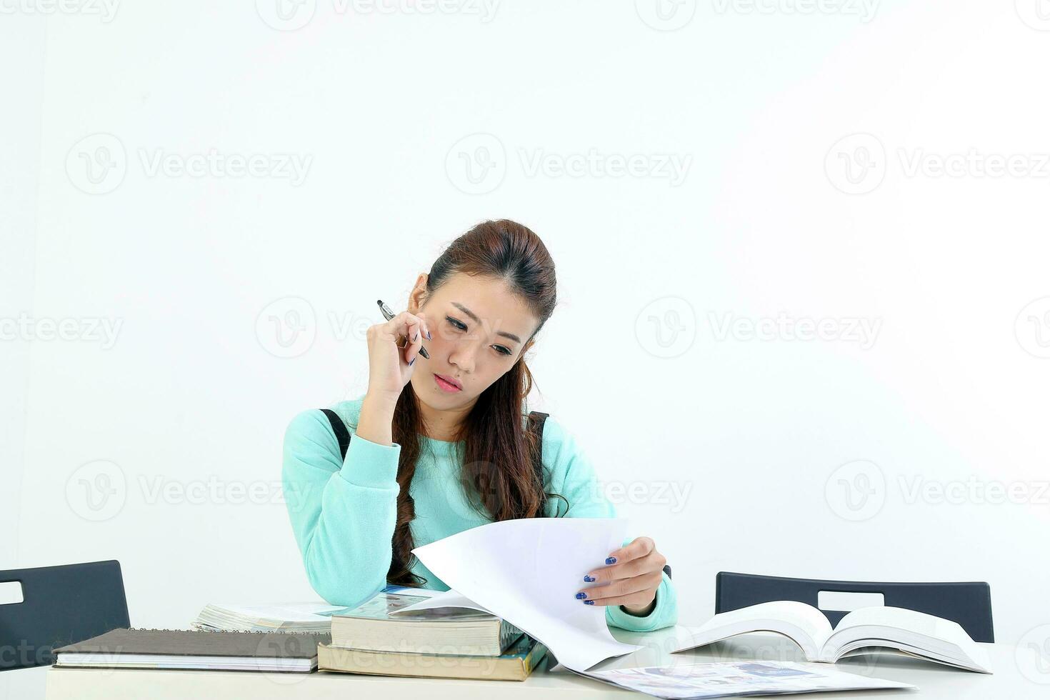 Yong ásia juventude menina dentro casual vestir sentar às mesa livro caderno caneta estude ler em branco fundo foto