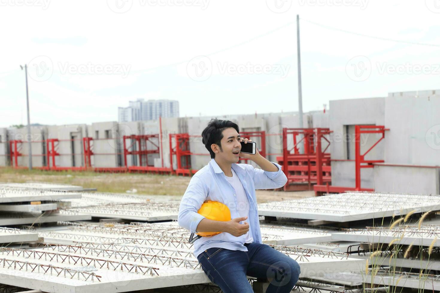 ásia homem malaio trabalhador engenheiro gestão Difícil segurança chapéu capacete às construção local segurando plano falando em telefone foto