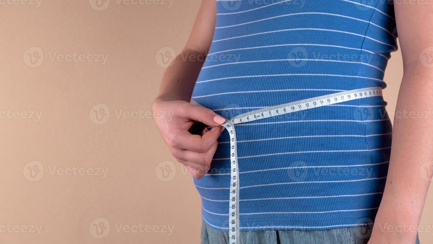 lindo corpo de mulher grávida com fita métrica foto