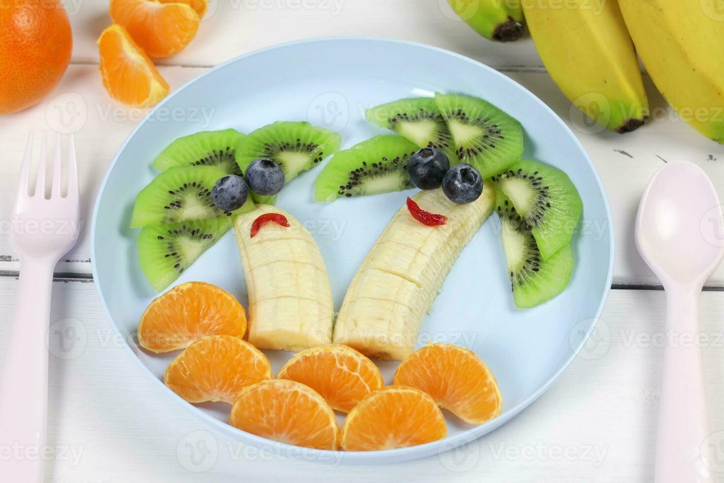 criativo Comida para uma criança, kiwi, tangerinas e banana. fruta Palmeiras. engraçado Comida em colori utensílios. fruta para uma criança. Visão a partir de acima. foto