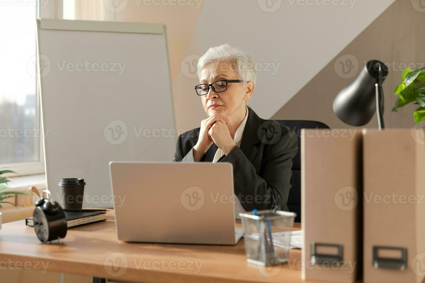 confiante à moda europeu meio envelhecido Senior mulher usando computador portátil às ambiente de trabalho. à moda Mais velho maduro anos 60 cinzento cabelos senhora empresária sentado às escritório mesa. patrão líder professor profissional trabalhador. foto