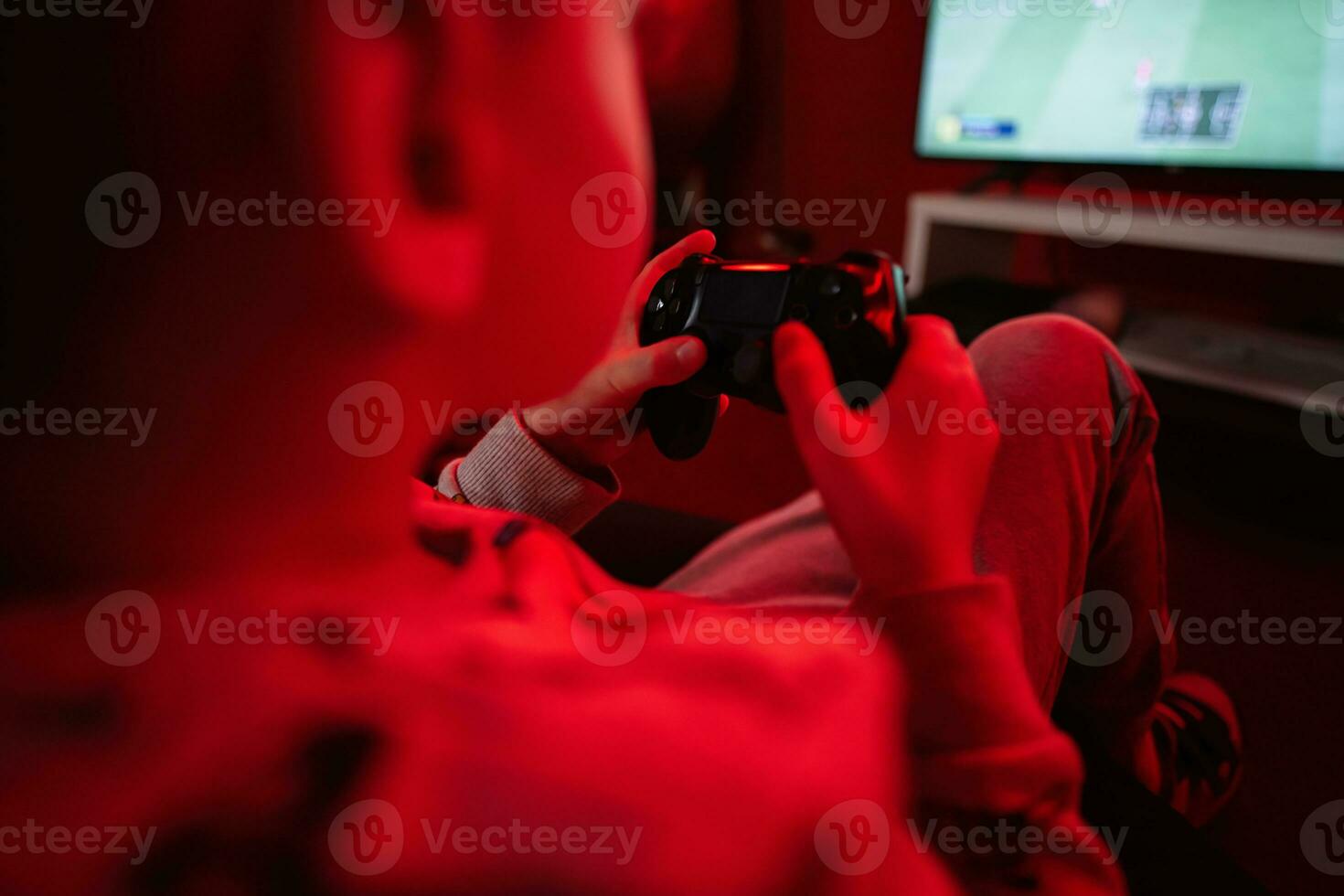 Garoto jogador jogar controle futebol vídeo jogos console dentro vermelho jogos sala. foto