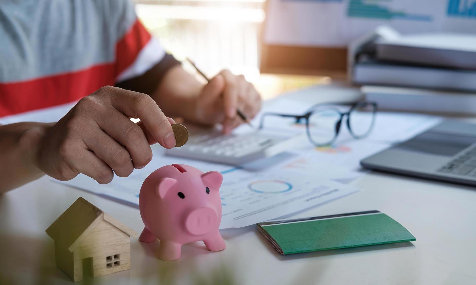 homem de negócios colocando o dinheiro no cofrinho para salvar o conceito de contabilidade financeira foto