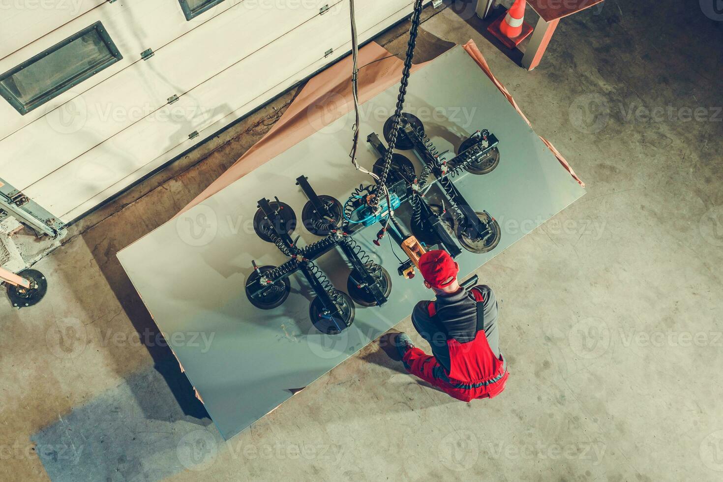 metalurgia Produção trabalhador usando vácuo lift para mover pesado metal folhas foto