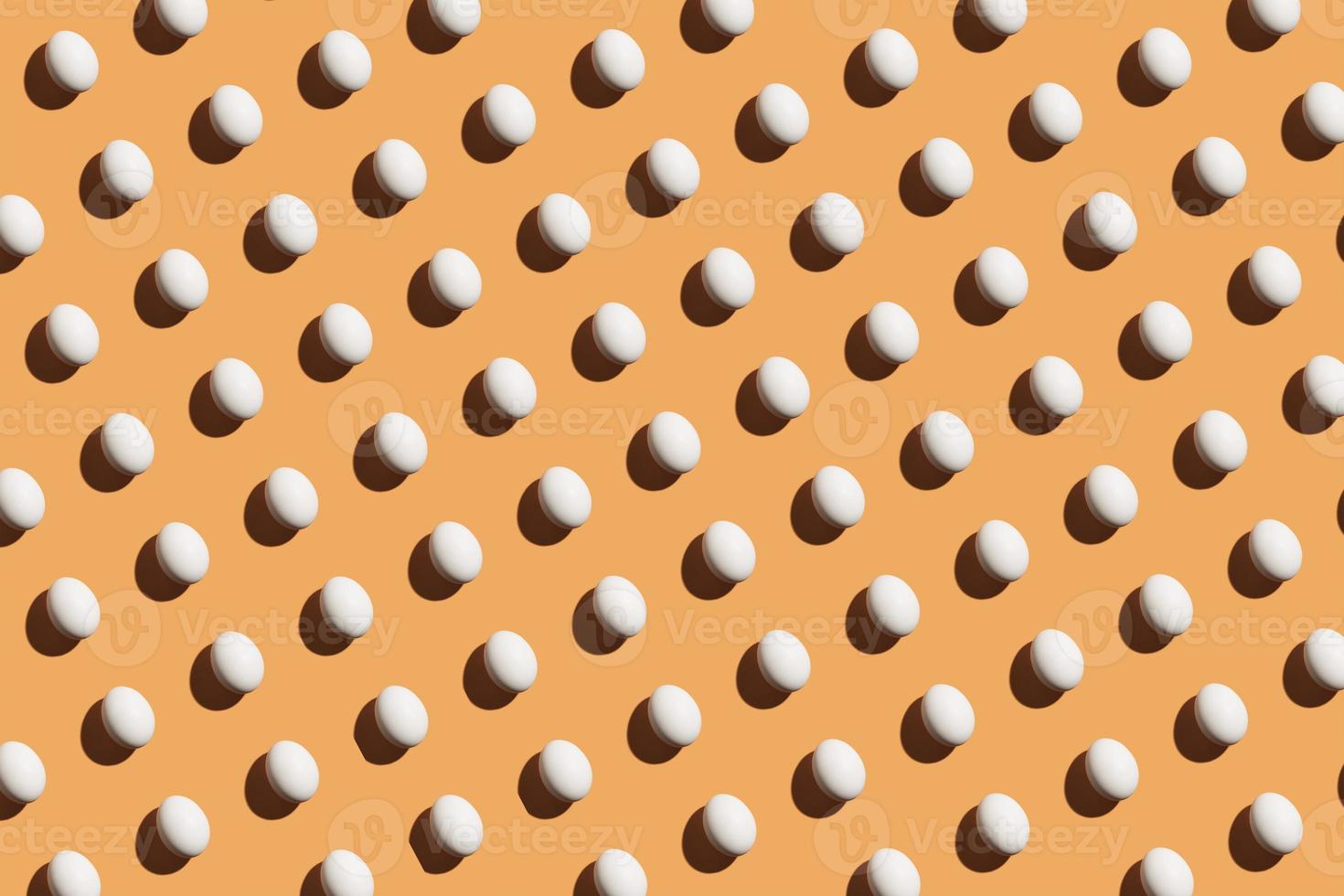 padrão mínimo feito de ovos brancos sob luz forte com sombras escuras em fundo laranja foto