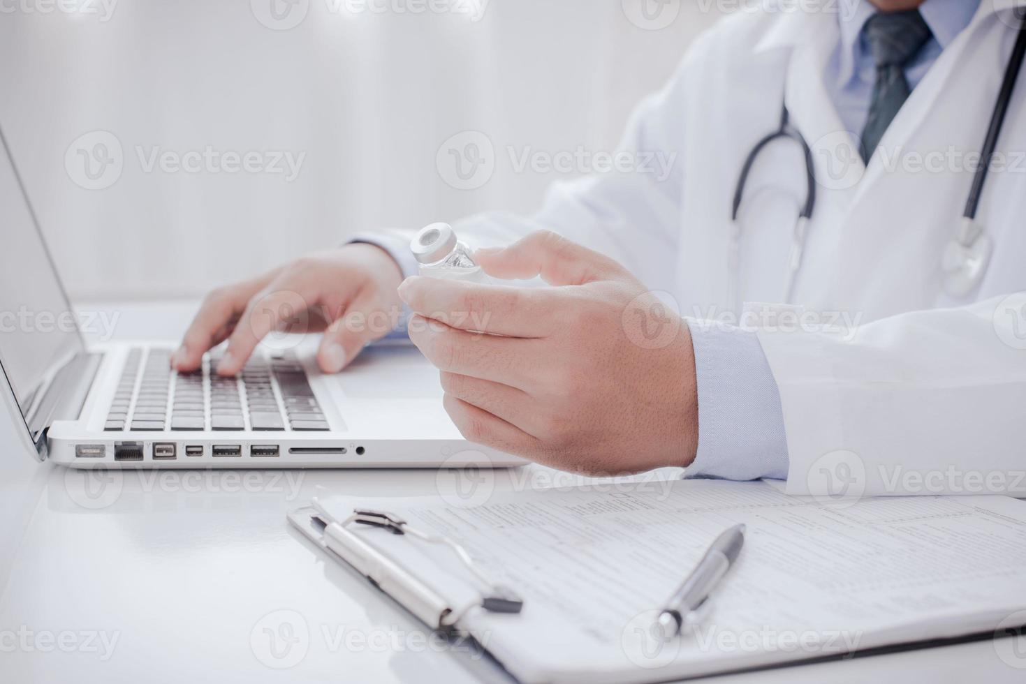 médico fazendo papelada e usando laptop na descrição da clínica em um computador servidor no conceito de hospital inventou uma vacina de cura para a doença coronavírus covid19 foto