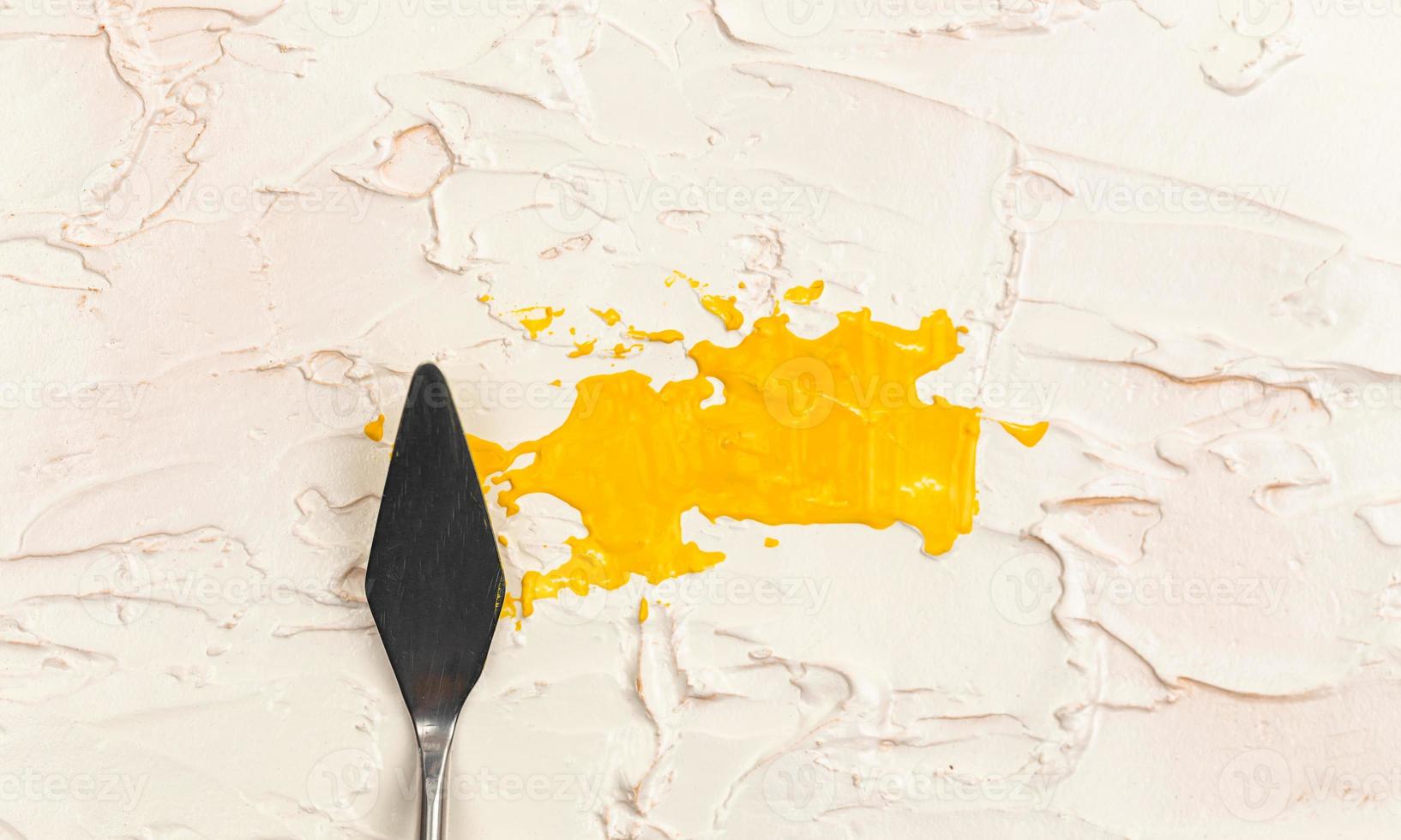 uma faca de paleta de pintura isolada em um fundo pintado de creme pintando de amarelo com espaço de cópia foto