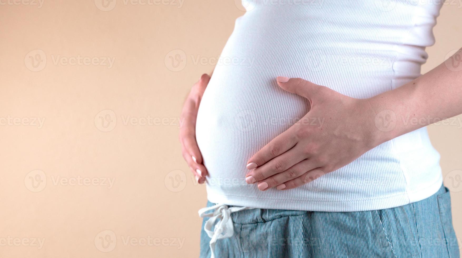 autêntico close up de uma jovem grávida de pijama acariciando sua barriga acabei de acordar em um quarto pela manhã foto