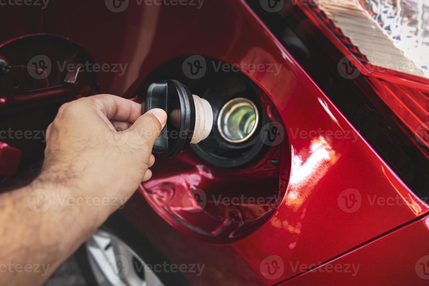 a mão humana está segurando a tampa do tanque de combustível do carro para abrir ou fechar foto