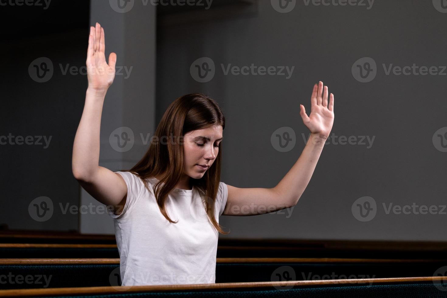 uma menina cristã de camisa branca está orando com o coração humilde na igreja foto