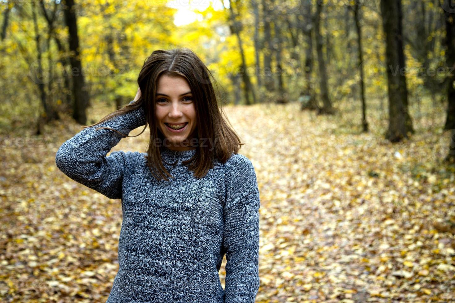 linda garota com um suéter cinza na floresta de outono foto