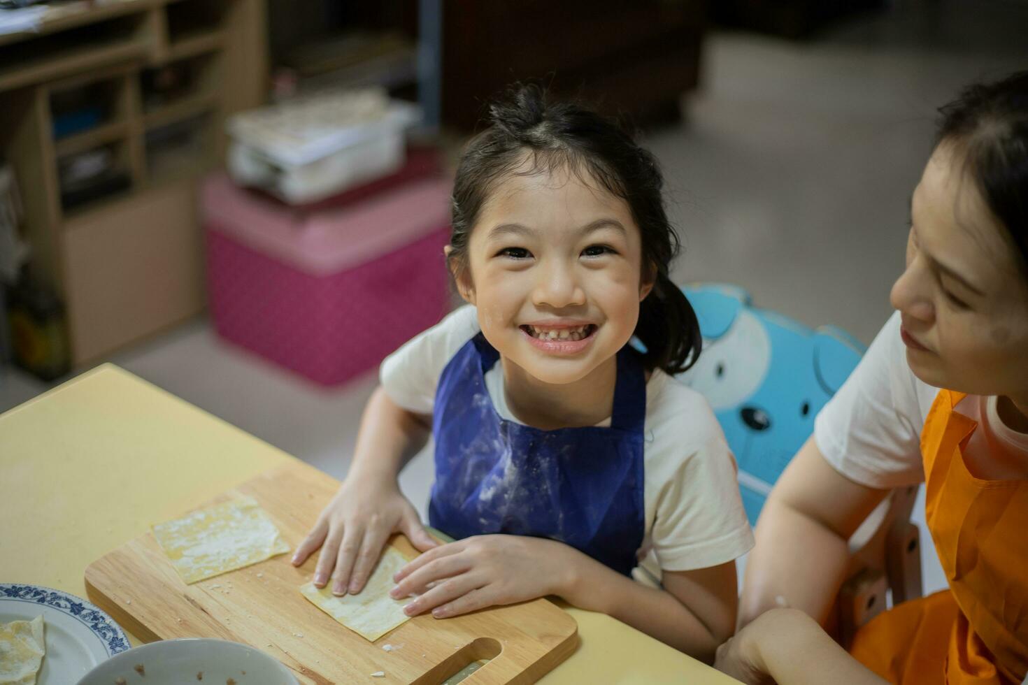 ásia mãe e filha estão cozinhando Comida e tendo Diversão dentro a cozinha. foto