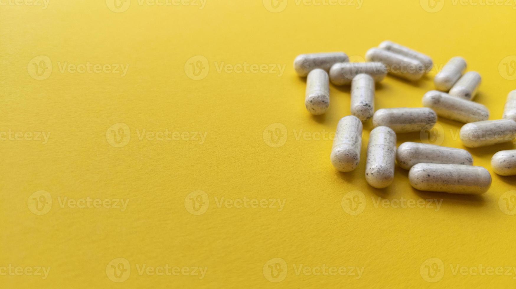 Comprimidos brancos sobre fundo amarelo simples plano com textura pastel e espaço de cópia foto de estoque de conceito médico